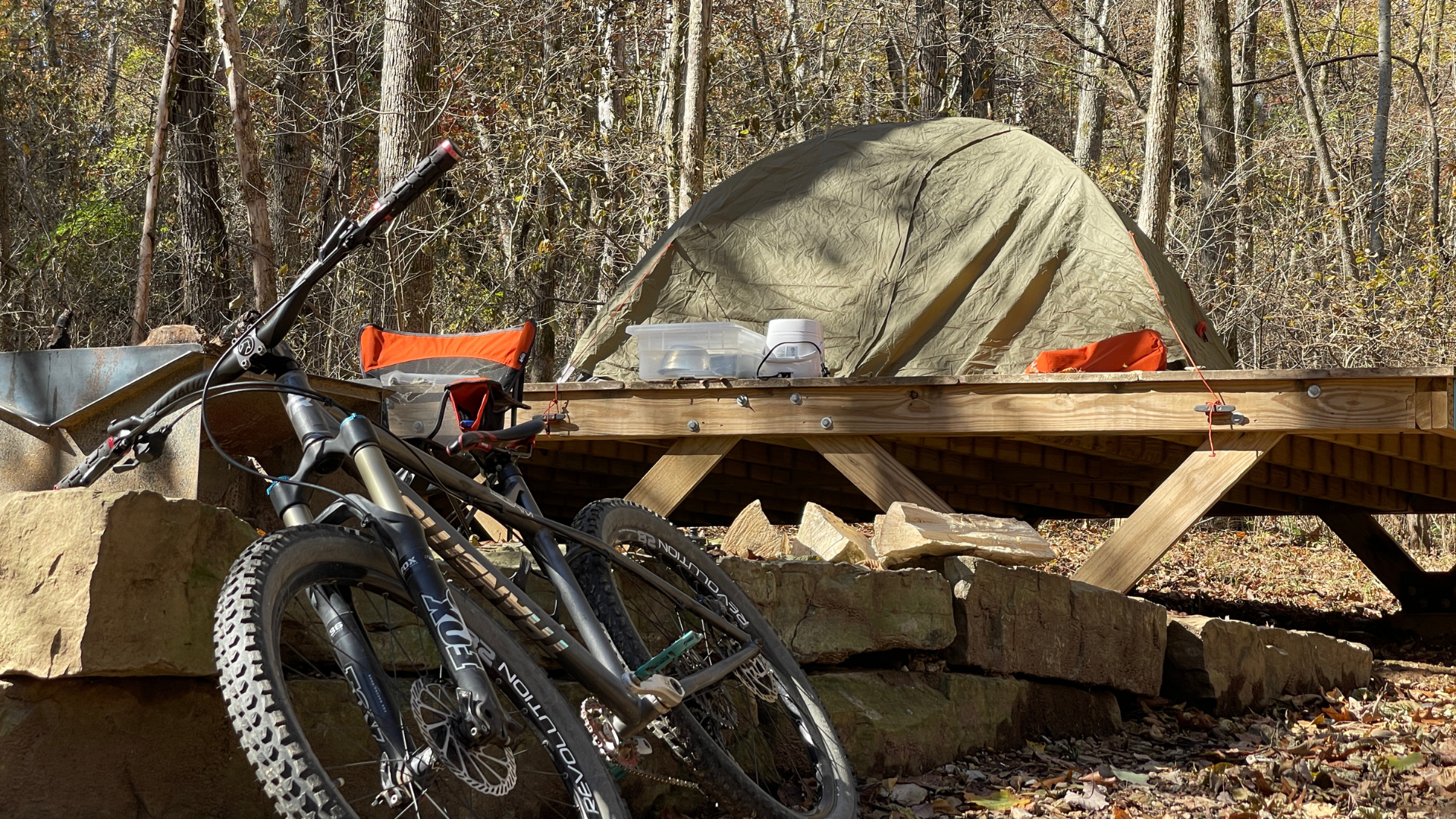 Camping tent on a wooden platform at Coler Mountain Bike Preserve. Mountain bike leaning in front.