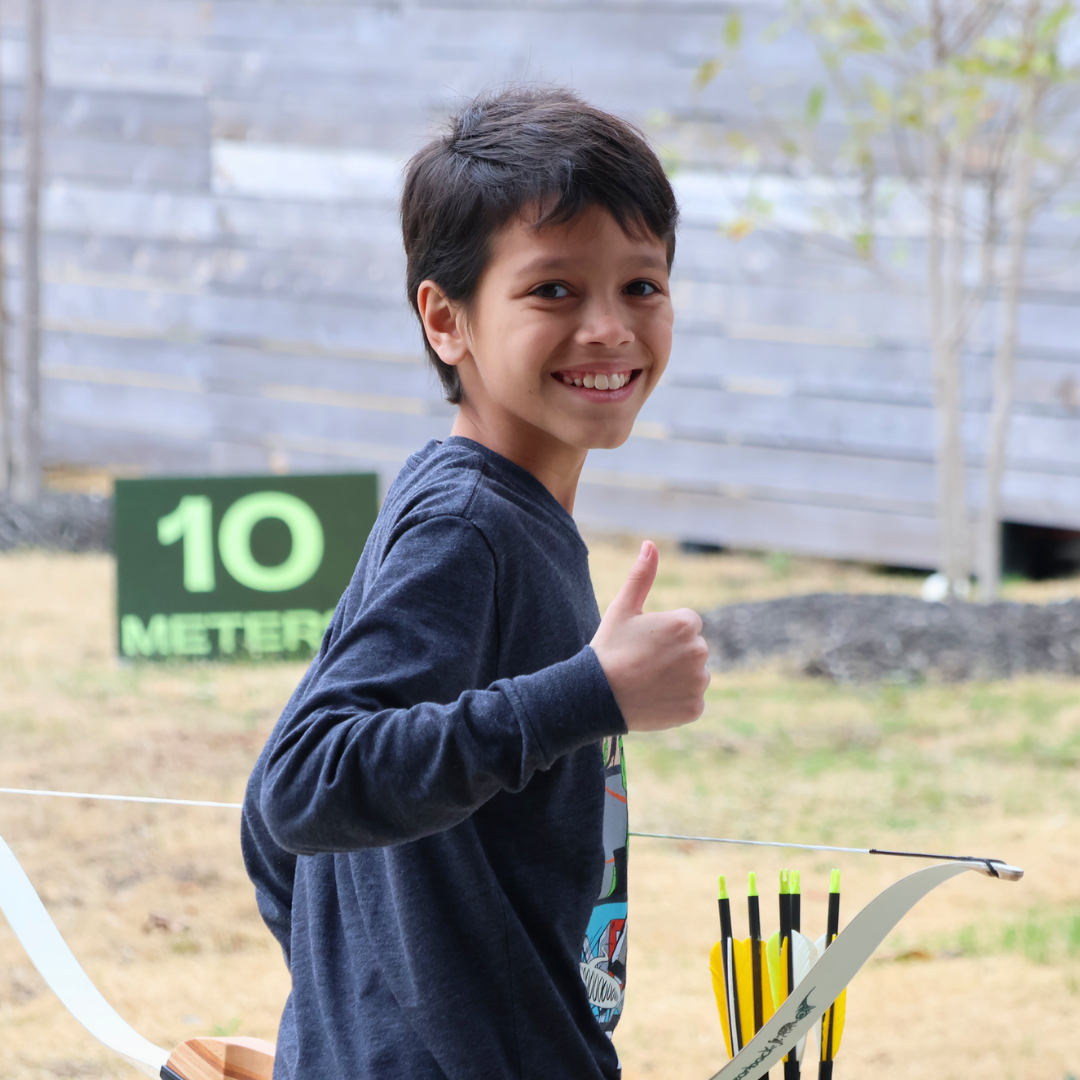 boy with a thumbs up while holding his bow at The Quiver Archery Range