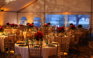 Christmas at Peel Museum in Bentonville Arkansas Fundraising Event for Non Profit Peel Compton Foundation gold tables inside a tent with poinsettia flowers on the tables and charger plates
