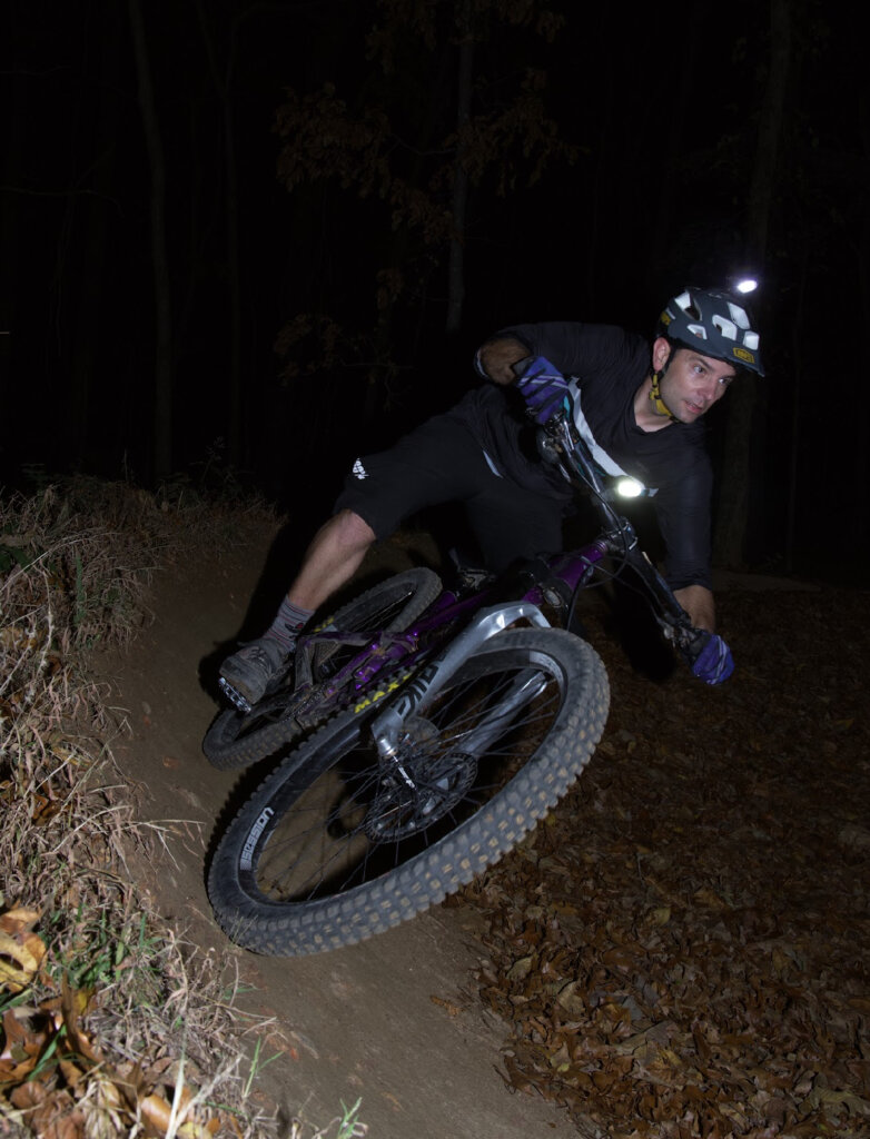 A photo of Chris Leis, Brand Ambassador, riding in the dark with a lit headlamp at Coler