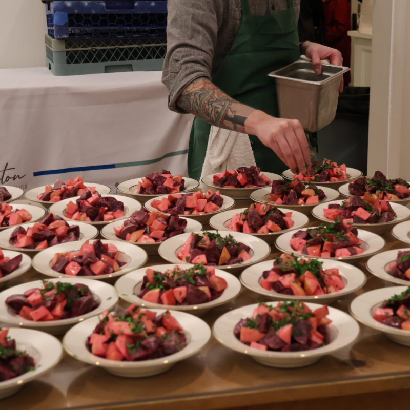 Table filled with plates of fancy dinner by Chef Matthew Cooper in Bentonville Arkansas of beet salad with greens on top at Peel Museum Fundraising Event