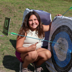 Girl points to the arrow she shot into a target at The Quiver
